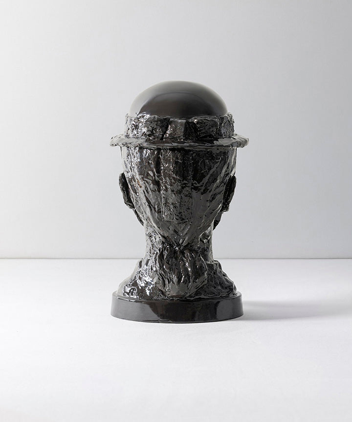 BRUTALIST BEAUTY | Black sculpture of a face with a helmet on a white background